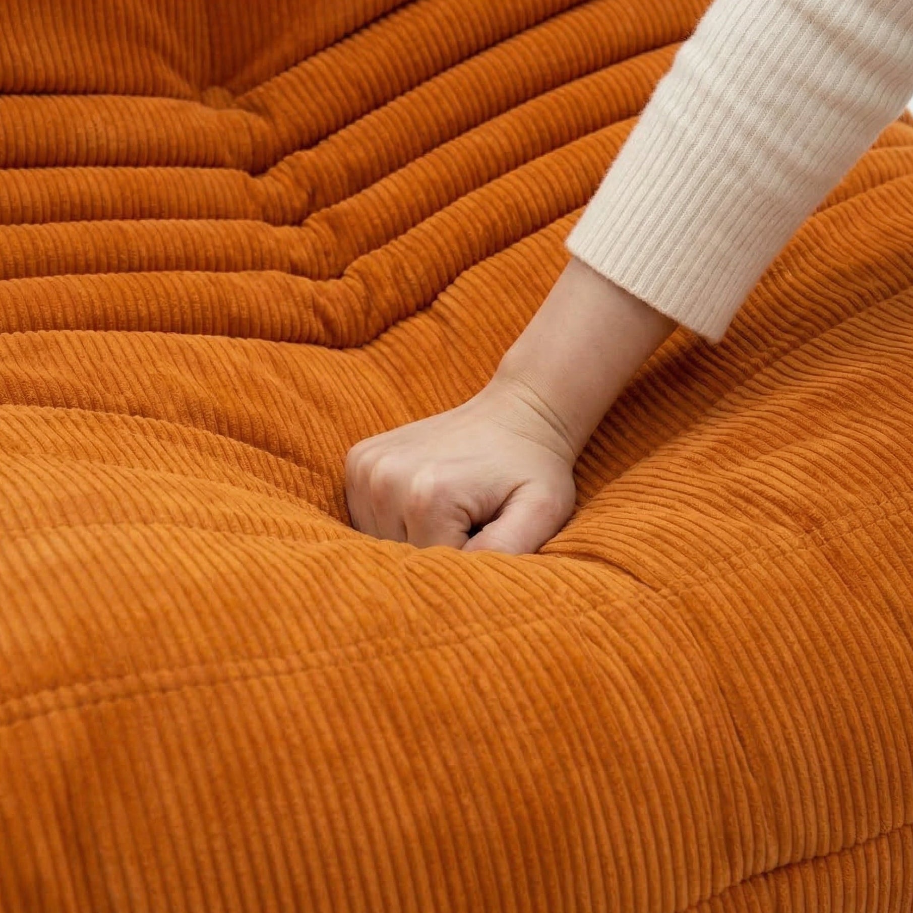 Hand peeking out from under an orange textured blanket